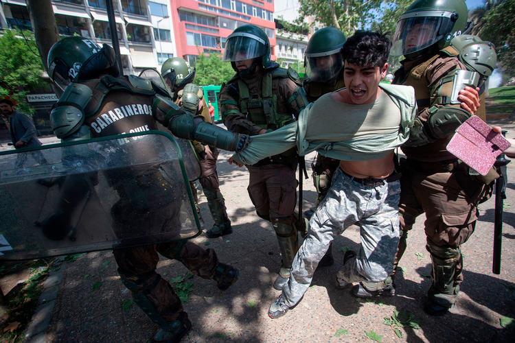 En demonstrant bliver anholdt af politiet i Santiago. Ifølge AP er 1500 mennesker blevet anholdt indtil videre.  Foto: Claudio Reyes/Ritzau Scanpix
