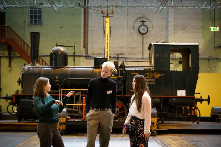 Selma Bergendal (tv), Jost Bech Tøndering og Astrid Kidon (th.) tager en pause fra ideudviklingen af nye studieture på skinner foran et veterantog i DSB's gamle lokomotivværksted nær Hovedbanen i København. Foto: Nima Taheri/POLFOTO