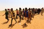 Migranter fra Etiopien, Sudan og Tchad går på grænsen til til Khartoum eskorteret af sudanske paramilitære styrker, efter smuglere har efterladt dem i en øde ørken tæt på grænsen til Libyen.  Foto: Mohamed Nureldin Abdallah/Ritzau Scanpix