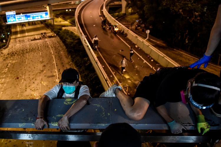 Demonstranter firede sig mandag nat lokal tid ned fra en motorvejsbro i et reb for at slippe væk fra Hongkongs Polytekniske Universitet og politiet. Da de nåede ned, blev de kørt væk af ventende motorcyklister. Foto: Ye Aung Thu/AFP
 Foto: Ye Aung Thu/Ritzau Scanpix