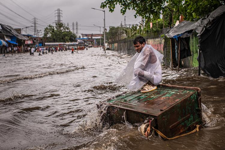En mand sidder på en skraldespand ved en flod i Mumbai. Klimaforandringer har gjort det indiske vejr mere ekstremt, og i år blev tørke direkte afløst af oversvømmelser.    Foto: Bryan Denton/Ritzau Scanpix