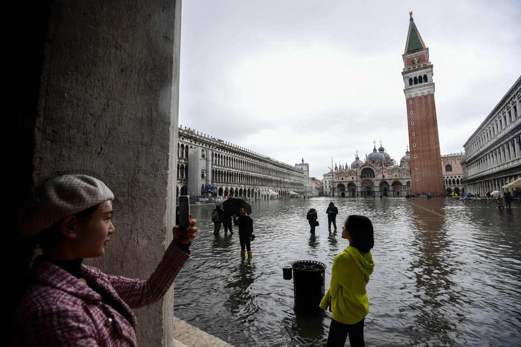 Adriaterhavet er trængt helt ind i Venedig. Turister tager billeder af Markuspladsen under vand.  Foto: Miguel Medina/Ritzau Scanpix