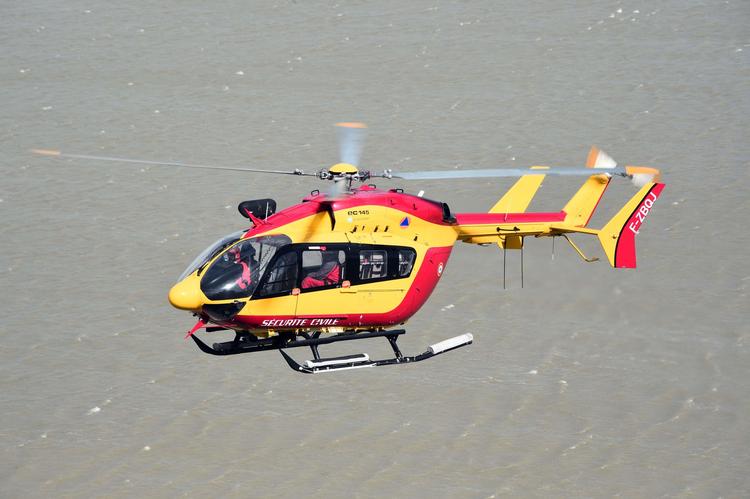En fransk civil helikopter flyver ved Mont-Saint-Michel i Normandiet under en stor evakueringsøvelse. Søndag aften mistede tre personer livet i en redningshelikopter.   Foto: Damien Meyer/Ritzau Scanpix
