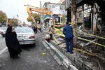 
    En kvinde ser til, mens demonstranter hænger et banner op på en afsvedet bank i Irans hovedstad, Teheran. Ifølge menneskeretsgruppen Center for Human Rights in Iran, er mellem 180 og 450 personer dræbt i løbet af fire dage med intens vold, efter at prisstigningerne på benzin blev offentliggjort 15. november Foto: Wana News Agency/Ritzau Scanpix