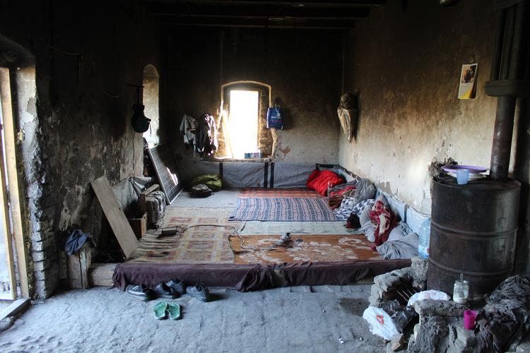 I denne forladte bygning bor en gruppe mandlige flygtninge i alle aldre. Der er iransk musik på telefonens højttaler, og en flok kaninunger render ind og ud og spiser madrester.  Foto: Camilla Egeborg Møller