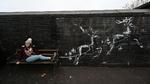 Der har været usædvanligt travlt foran en ellers uanselig bænk i Birmingham, efter Banksy prægede væggen ved siden af den med to hvide rensdyr i sidste uge.  Foto: Paul Ellis/Ritzau Scanpix