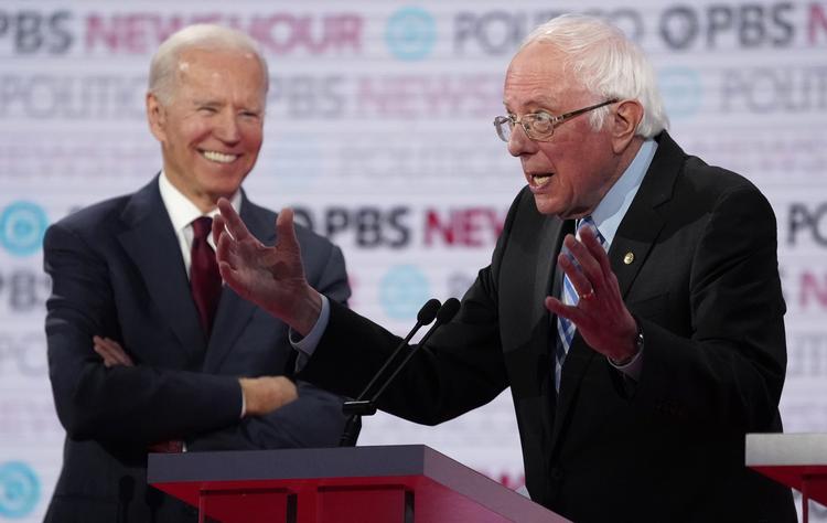 Joe Biden griner, mens Bernie Sanders taler ved nattens dagens debat mellem de demokratiske præsidentkandidater. Foto: Mike Blake/Ritzau Scanpix
