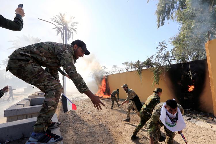 Demonstranter fra Hashd al-Shaabi-militsen tænder bål op ad muren omkring den amerikanske ambassade i Bagdad. Foto: Thaier Al-sudani/Ritzau Scanpix