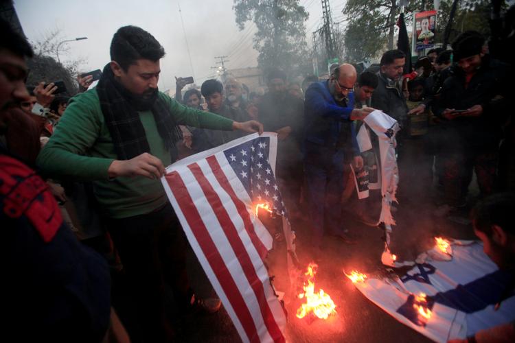 Under en protest i Pakistan, brænder tilhængere af den afdøde Qassem Sulaimani det amerikanske og det israelske flag. De mener, at de to lande har samarbejdet om droneangrebet. Foto: Mohsin Raza/Ritzau Scanpix
