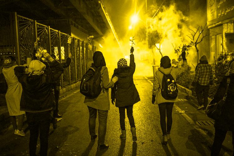 Iranere med blomster i hænderne demonstrerer foran Amir Kabir-universitetet i Teheran i en sky af tåregas, som politiet har affyret. Demonstrationerne blev udløst efter Irans nedskydning af et ukrainsk passagerfly, som kostede 176 mennesker livet, heriblandt mange iranere.  Foto: AFP/Ritzau Scanpix