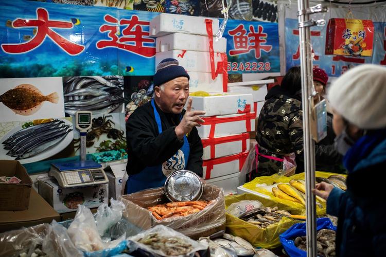 En fiskehandler forsøger at afsætte sine varer på et marked i Beijing. Landets bruttonationalprodukt voksede med 6,1 procent sidste år, og det var den laveste vækst i knap tre årtier.  Foto: Nicolas Asfouri/Ritzau Scanpix