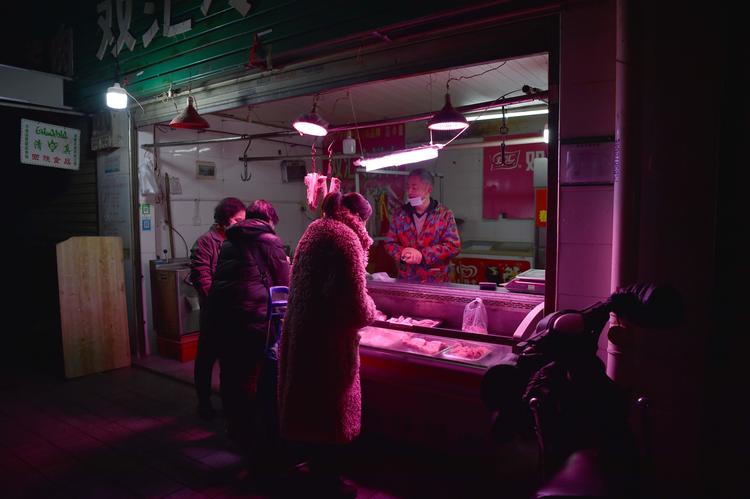 Folk iført ansigtsmaske kæber ind på markedet i Wuhan. Normalt plejer det at være fyldt med mennesker. Foto: Hector Retamal/Ritzau Scanpix