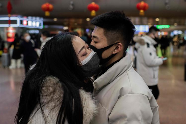 Et par kysser hinanden farvel i Beijing og har som sikkerhedsforanstaltning masker på.  Foto: Nicolas Asfouri/Ritzau Scanpix