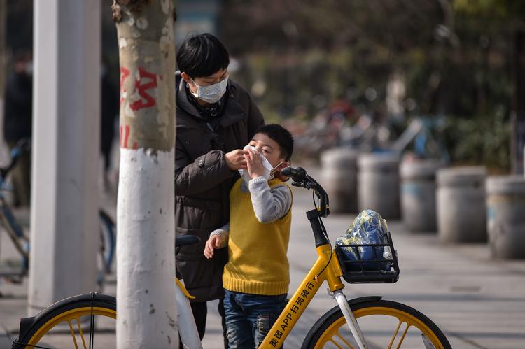 En mor hjælper sin søn med masken i den virus-ramte kinesiske provins Hubei . Foto: Hector Retamal/Ritzau Scanpix