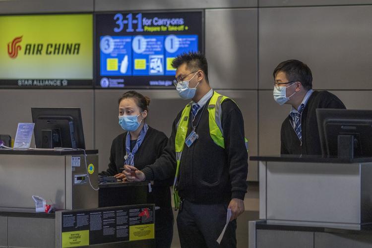 Ansatte fra det kinesiske  luftfartsselskab Air China bærer maske ved indtjekningsskranken i lufthavnen i San Francisco. Foto: David Mcnew/Ritzau Scanpix