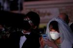 Et brudepar bærer masker som beskyttelse mod coronavirus i forbindelse med et massebryllup i South Korea. WHO melder om alvorlig global mangel på både mundbind og beskyttelsesdragter. Foto: Heo Ran/Ritzau Scanpix