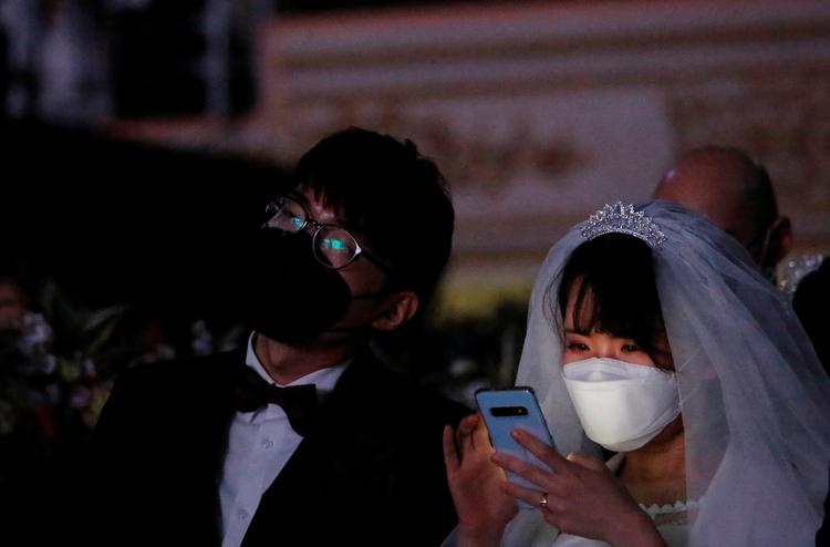 Et brudepar bærer masker som beskyttelse mod coronavirus i forbindelse med et massebryllup i South Korea. WHO melder om alvorlig global mangel på både mundbind og beskyttelsesdragter. Foto: Heo Ran/Ritzau Scanpix