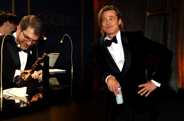 Brad Pitt hygger sig, mens han får sit navn indgraveret i Oscar-statuetten. Foto: Eric Gaillard/Ritzau Scanpix