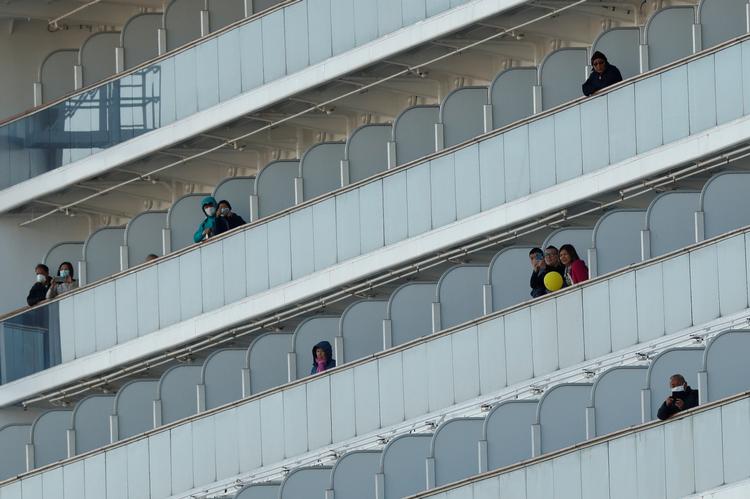 Passagerer står på deres balkoner på krydstogtskibet 'Diamond Princess' i Yokohama, syd for Tokyo, hvor skibet ligger for kaj. 60 passagerer har fået konstateret coronoavirus. Foto: Kim Kyung-hoon/Ritzau Scanpix