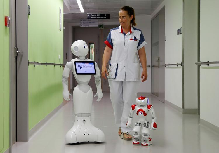 En sygeplejerske går sammen med 'Pepper' og 'Zora' - to robotter, som byder patienter og pårørende velkommen på AZ Damiaan hospital i Ostend, Belgien. I sit første store udspil som næstformand for EU-Kommissionen vil Margrethe Vestager ruste Europa digitalt. At tøjle den kunstige intelligens er afgørende. Foto: Francois Lenoir/Ritzau Scanpix