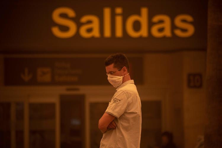 En mand venter udenfor Tenerifes South-Reina Sofia lufthavn under en sandstorm søndag den  23. februar. En italiensk turister på den spanske ø er smittet med coronavirus.  Foto: Desiree Martin/Ritzau Scanpix