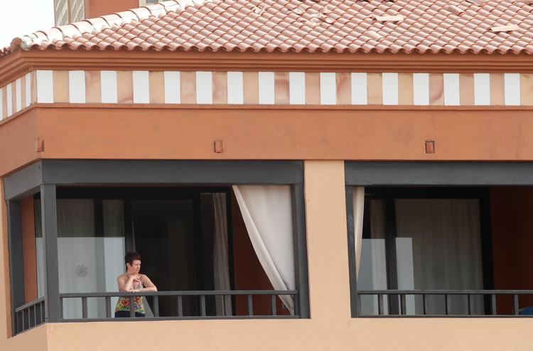 En kvinde kitger ud af vinduet fra det lukkede H10 Hotel på Tenerife.  Foto: borja suarez/Ritzau Scanpix
