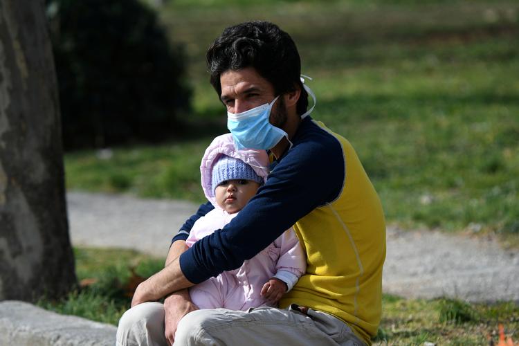  En mand sidder med en baby udenfor AHEPA hospital i  Thessaloniki, hvor det første bekræftede tifælde af coronavirus er konstateret.  Foto: Alexandros Avramidis/Ritzau Scanpix