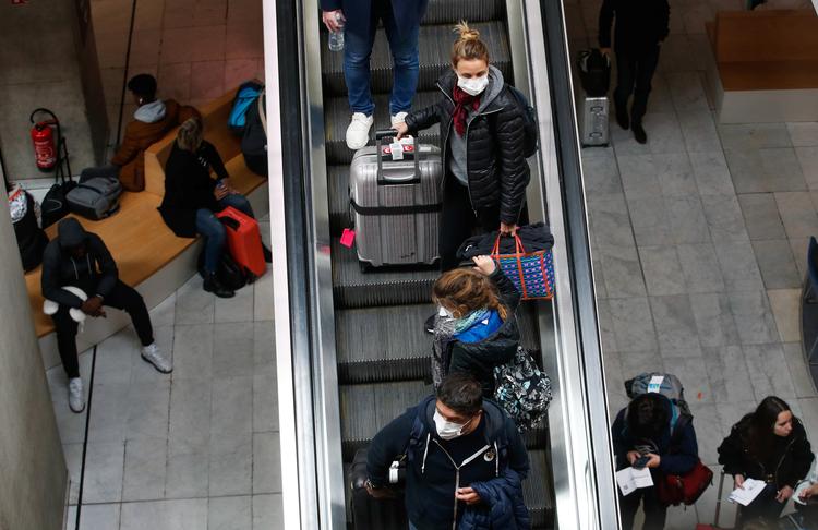 Folk bærer ansigtsmaske, da de ankommer til  Charles de Gaulle lufthavn ved Paris. Frankrig forbyder ny forsamlinger med over 5.000 mennesker i forsøget på at bremse coronavirus.  Foto: Gonzalo Fuentes/Ritzau Scanpix