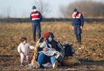 Migranter hviler sig ved Pazarkule, en af Tyrkiets grænser til Grækenland, med tyrkiske gendarmere bag dem.  Foto: Leonhard Foeger/Ritzau Scanpix