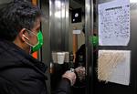 En mand i Iran bruger en tandstikker til at trykke på en knap i en elevator for at undgå at blive smittet og sprede smitte af coronavirus. Foto: Atta Kenare/Ritzau Scanpix