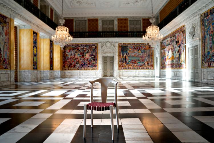 Kongehusets nye stol skal blandt andet bruges i taffelsalen på Christiansborg Slot. Her får den selskab af Bjørn Nørgaards farvestrålende gobeliner.  Foto: Keld Navntoft, Kongehuset