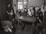 Her ses en mor med sine syv børn i et typisk arbejderhjem i slutningen af 1920'erne. Her måtte man tilsyneladende godt have fødderne på bordet. Foto: Arbejdermuseet