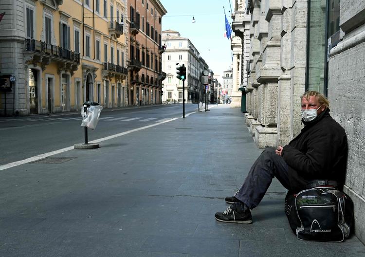 En hjemløs sidder på gaden Via del Corso i det centrale Rom. Landet har indført straf på op til fem års fængsel kan være konsekvensen i Italien, hvis man bryder karantæneregler efter virussmitte.   Foto: Vincenzo Pinto/Ritzau Scanpix