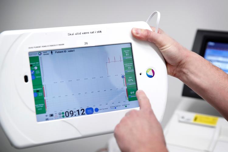På en tablet kan sundhedspersonalet se, om der er ændringer i patienternes tilstand. På den måde kan en sygeplejerske holde øje med mange coronasyge på én gang, uden at skulle komme tæt på dem.  Foto: Jens Dresling/POLFOTO
