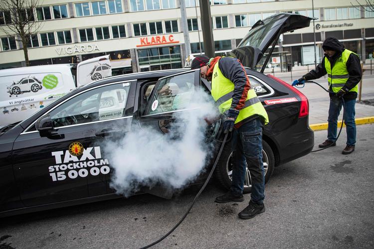 To mænd desinficerer en taxa i Stockholm. Foto: Jonathan Nackstrand/Ritzau Scanpix