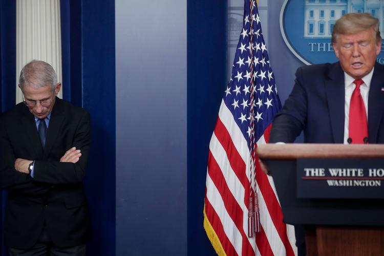 Donald Trump taler om coronakrisen, mens direktøren for den amerikanske udgave af Sundhedsstyrelsen, Anthony Fauci, lytter. Foto: Jonathan Ernst/Ritzau Scanpix