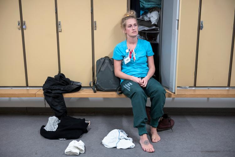 Maria Burin Møller sidder træt i omklædningen efter en aftenvagt, lige efter de første coronapatienterne kom.  Hun er intensivsygeplejerske på Hvidovre Hospital og plejer de hårdest ramte patienter med Covid-19. Politiken følger hendes hverdag. Foto: Sofia Busk/Sofia Busk
