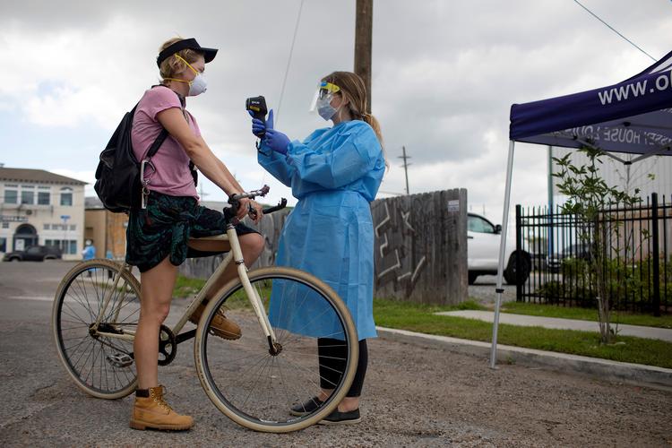 En cyklist får taget sin temperatur i et drive-in testcenter i New Orleans. I USA er der nu over 100.000 mennesker, som er bekræftet smittet med coronavirussen. Foto: Kathleen Flynn/Ritzau Scanpix