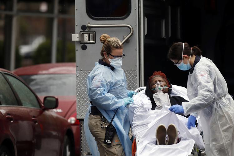 Reddere i beskyttelsesdragter hjælper en syg patient op i en ambulance i New York, lørdag. Byen er hårdt ramt af coronaepidemien. Foto: Stefan Jeremiah/Ritzau Scanpix