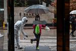 En hotelansat i beskyttelsesdragt sprayer nyankomne gæster til et hotel i Wuhan. Foto: Hector Retamal/Ritzau Scanpix