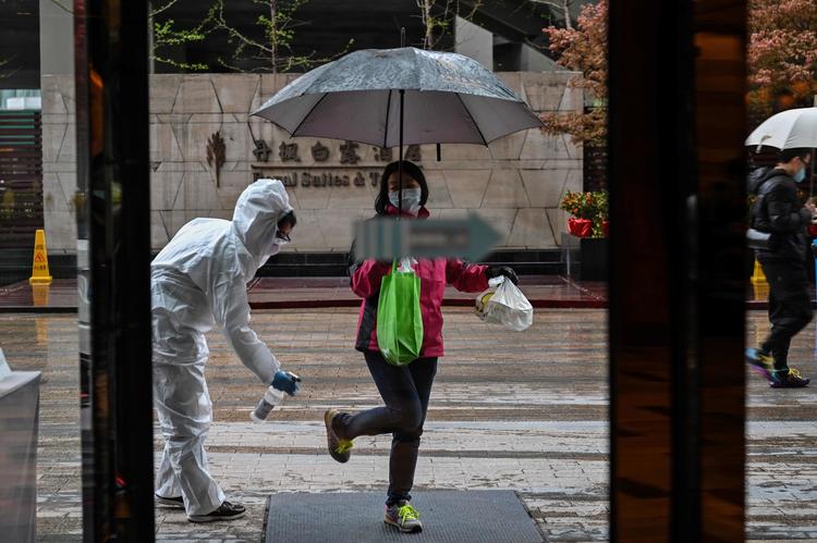 En hotelansat i beskyttelsesdragt sprayer nyankomne gæster til et hotel i Wuhan. Foto: Hector Retamal/Ritzau Scanpix