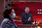 En kvinde med maske passerer billedet af den kinesiske præsident, Xi Jinping på en gade i Shanghai. Pandemien kan bremse Kinas økonomiske vækst og blive et hårdt slag for de østasiatiske lande. Foto: Aly Song/Ritzau Scanpix