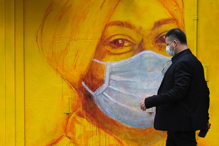Ansigtsmasker har siden SARS-epidemien i 2003 været standardudstyr i Hongkong.  Det er de også under corona-krisen, hvor både vægmalerier og indbyggere har maske på. Foto: Tyrone Siu/Ritzau Scanpix