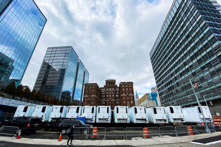 En kvinde passerer en række midlertidige kølevogne, der er indrettet som midlertidige lighuse uden for Bellevue Hospital i New York, der er hårdest ramt af coronaen i USA. Foto: Eduardo Munoz/Ritzau Scanpix