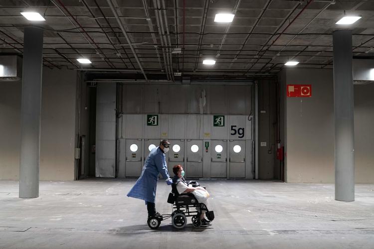 En patient bliver skubbet i sin kørestol på et midlertidigt hospital for COVID-19-patienter i Madrid.  Foto: Handout/Ritzau Scanpix