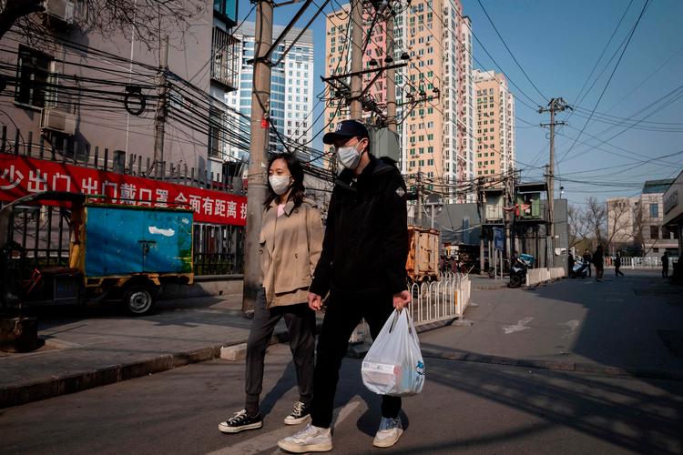 KIna er lige så langsomt ved at åbne dele af landet efter coronavirus. Her et fotografi fra Beijing, 29. marts 2020. Personerne på fotoet indgår ikke i historien om hundeluftningen. Foto: Nicolas Asfouri/Ritzau Scanpix