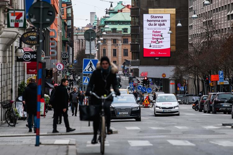 'Bliv hjemme hvis du er syg', står der på banneret bag cyklisten i Stockholm i går.  Foto: Jonathan Nackstrand/Ritzau Scanpix