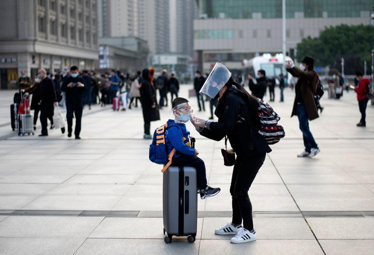 En kvinde retter på sit barn, inden de skal med toget på banegården i Wuhan. Foto: Noel Celis/Ritzau Scanpix