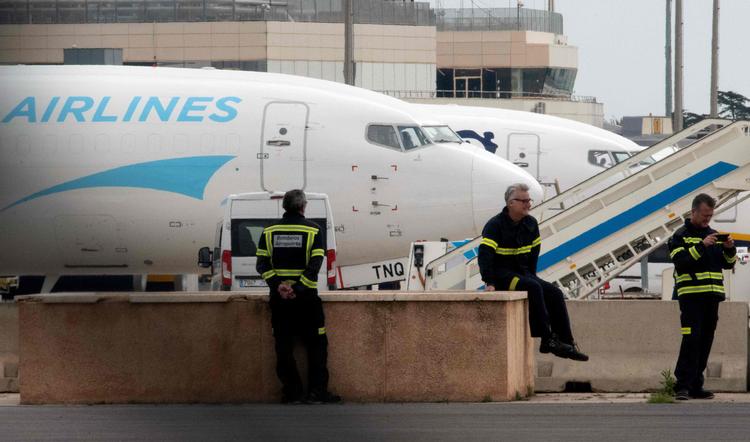 Spanske brandmænd holder pause i Valencias lufthavn. Over hele kloden bliver fly på jorden på grund af coronakrisen. Foto: Jose Jordan/Ritzau Scanpix