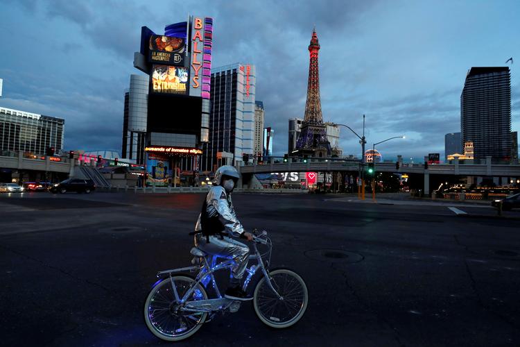 En mand på cykel står på Las Vegas strip. De amerikanske  corona-restriktionløber frem til 30. april. Nu overvejer Trump, hvornår de skal hæves. Foto: Shannon Stapleton/Ritzau Scanpix